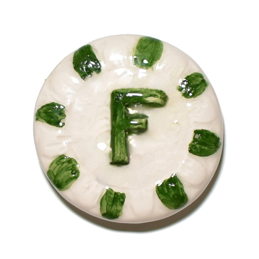 Esempio di ceramica smaltata con la Cristallina CLA 3 Trasparente Lucida Apiombica, raffigurante una decorazione con la lettera "F" in verde e dettagli verdi su fondo bianco, Smalti, Colori e Cristalline, Cristalline Lucide AP VLA, Colori Apiombici, Cristallina Neutra, AVADA - Best Sellers, Collezione Ditta Fauci, AVADA Email Marketing - Best Sellers, AVADA Email Marketing - Newest Products
