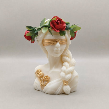 Candela Dea Bendata con treccia, corona di foglie verdi e rose rosse, benda e fiori rifiniti in oro