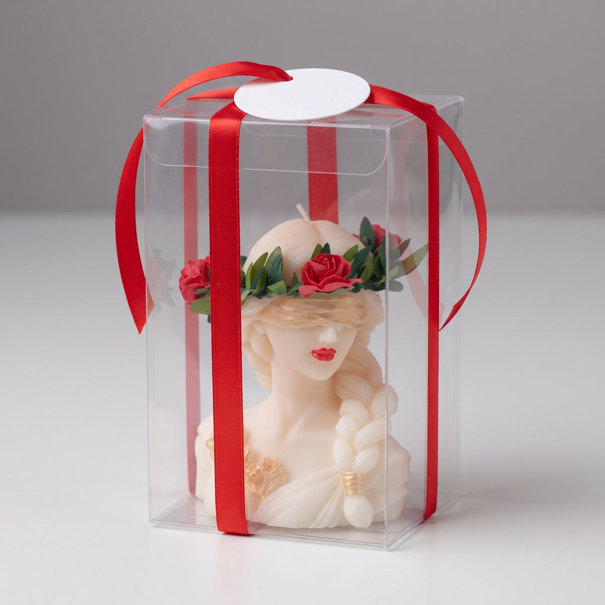 Candela Dea Bendata con treccia nella confezione regalo trasparente con nastro rosso ed etichetta